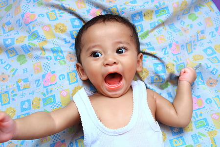 baby in white tank top with open mouth