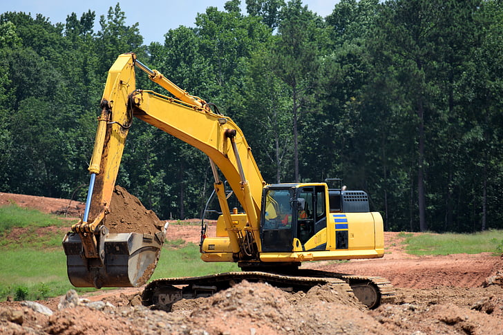 yellow excavator excavating on ground