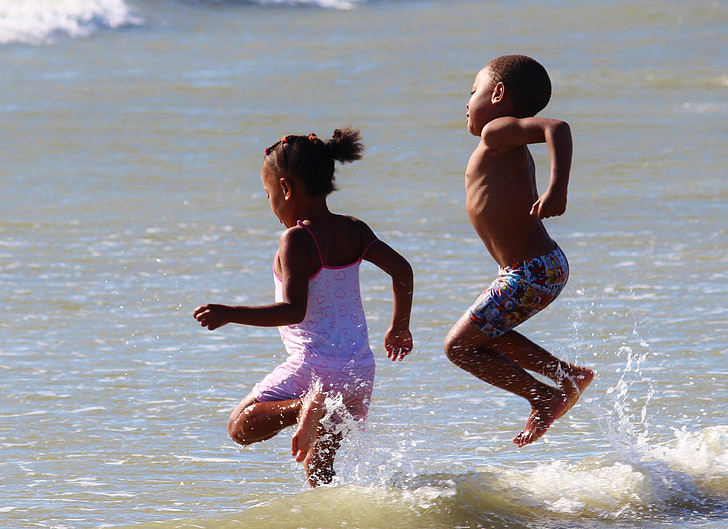girl and boy playing on water during daytime