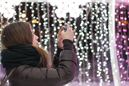 woman taking photo near string lights