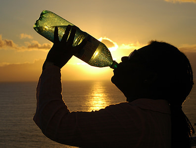 silhouette of person drinking on bottle
