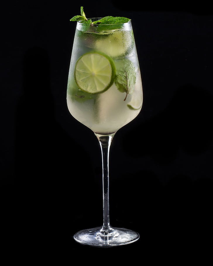 glass of beverage with lime on black surface
