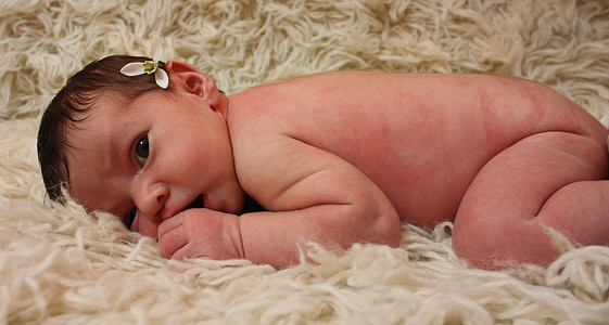baby lying on beige fur textile
