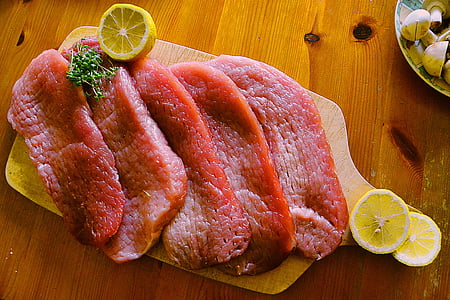 five medium rare meat with lemon on brown wooden chopping board