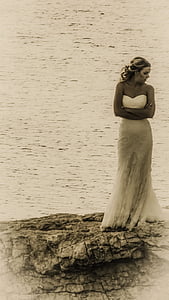 woman standing on stone near sea