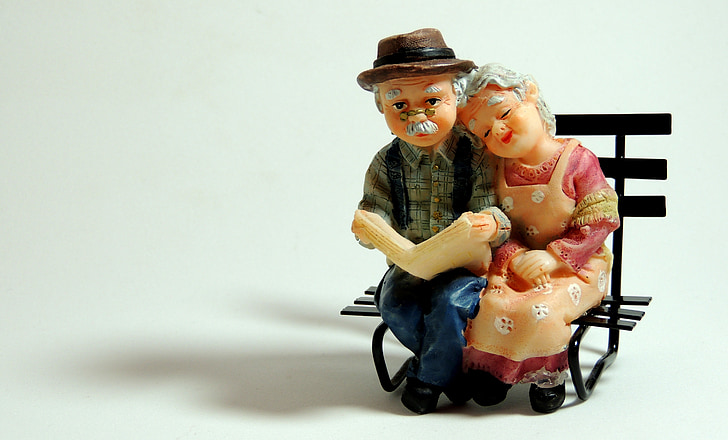 man and woman figurines sitting on black wooden bench