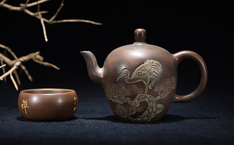 brown teapot near bowl on blue surface