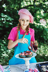 girl wearing blue apron designing cupcake during daytime
