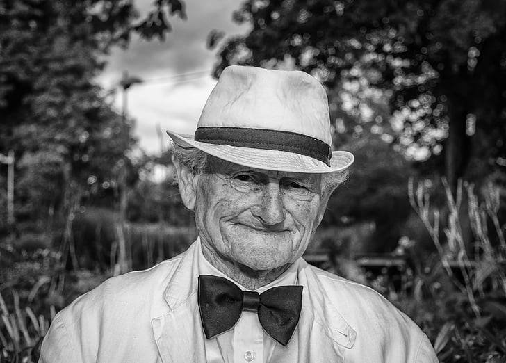 grayscale photo of man wearing formal suit and bucket hat