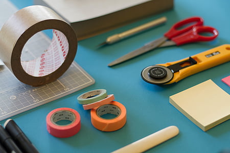 closeup photography of electrical tapes near scissors and post-it note