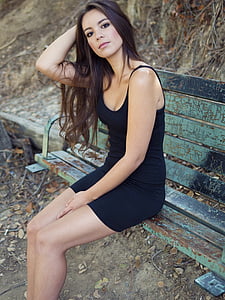 woman in black mini dress sitting on blue wooden bench