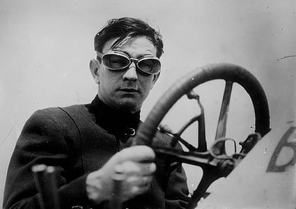 grayscale photography of man wearing goggles holding steering wheel