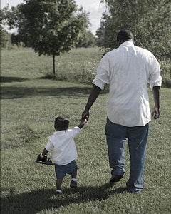 man and toddler walking wearing white long-sleeves shirts