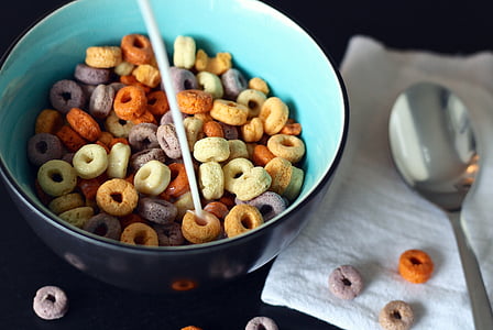 milk poured onto cereals in bowl next to spoon