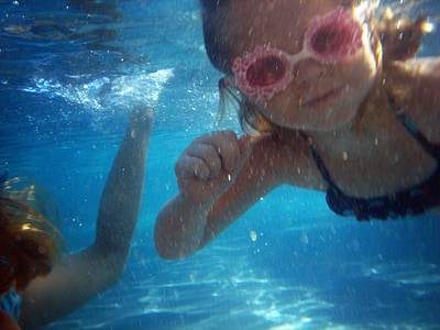 toddler wearing pink swimming goggle under the body of water