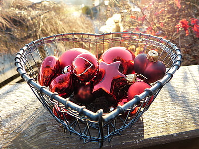 red Christmas baubles in gray wire heart bowl