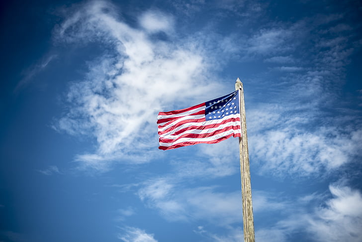 USA flag under white clouds during daytime