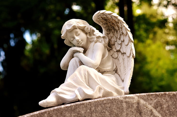 focus photography of female angel statuette