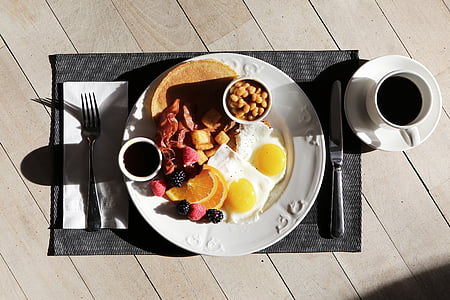 plate of egg, berries, and pancake with a cup of coffee