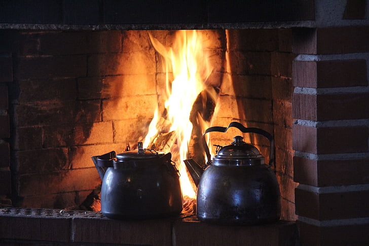 two gray kettles on brown fireplace