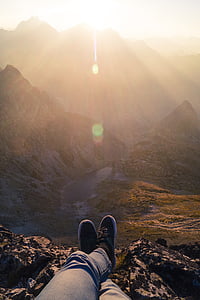 person sitting on rock near mountain range
