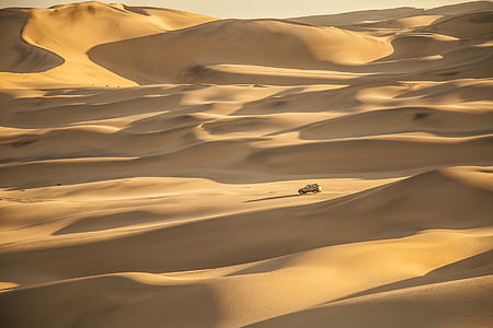 beige vehicle on sand dunes