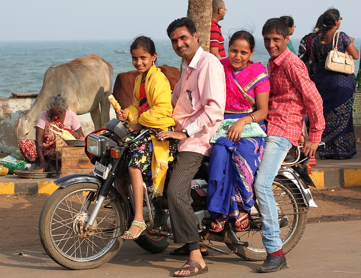 group of people riding motorcycle on road near body of water during daytime