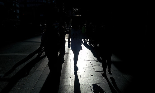 silhouette photo of people walking on concrete road