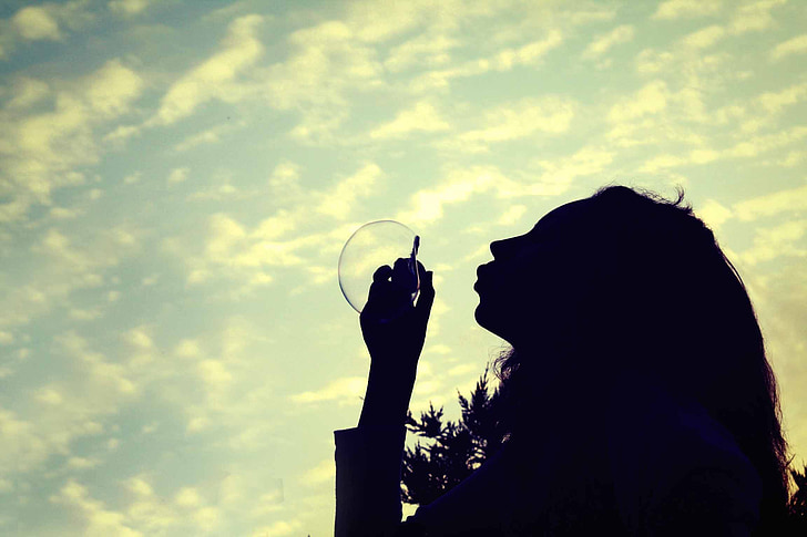 silhouette photo of woman making bubble