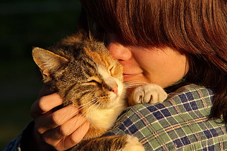 woman cuddling calico cat