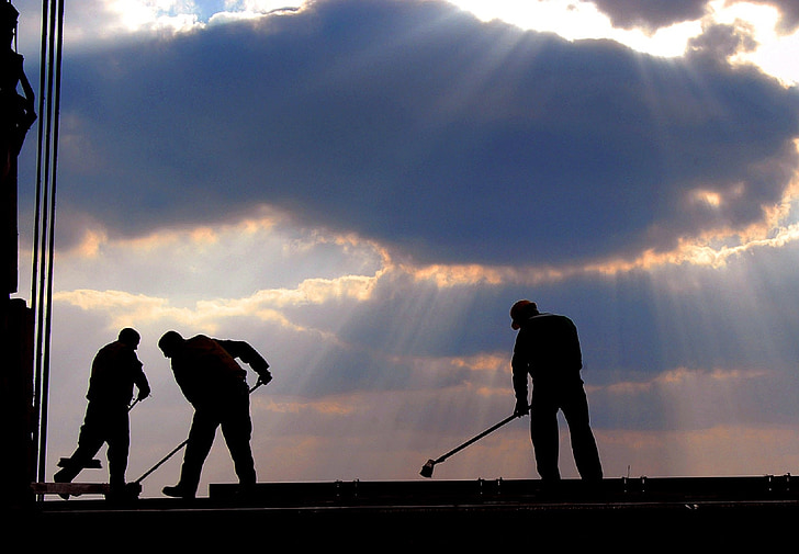 men working under the cloudy sky