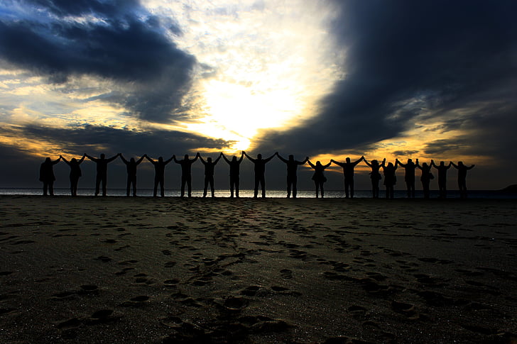 silhouette of group of people raising their hands