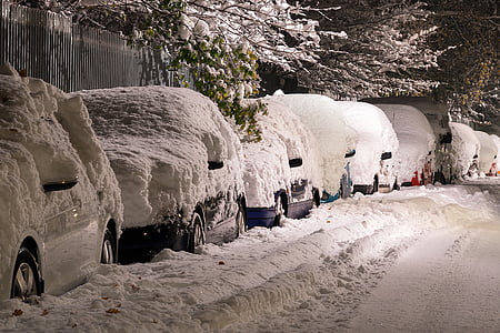 snow covered vehicles on the road during nighttime