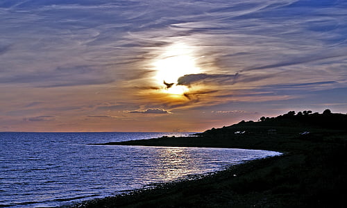 silhouette of island near shoreline during golden hour