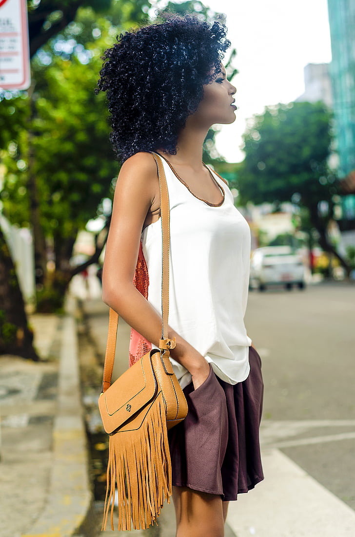woman in white tank top with brown leather shoulder bag standing on street during daytime