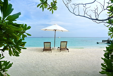 two lounge chair under umbrella on seashore