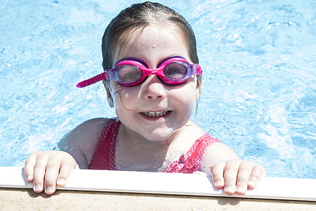 girl wearing swimming goggles soaking on body of water