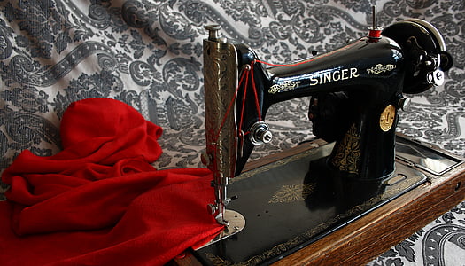 black and brown Singer sewing machine and red textile
