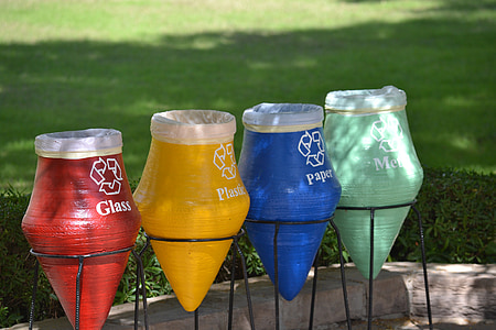 four assorted-color garbage pots near green grass field