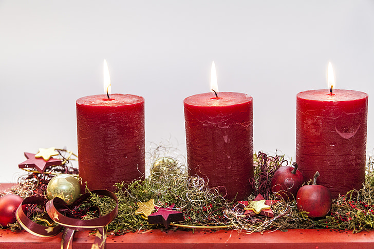 focus photo of three red lighted pillar candles