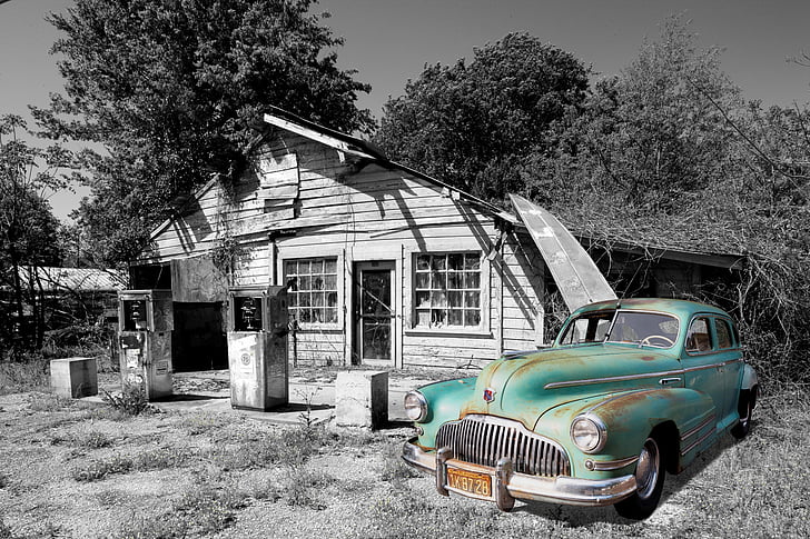 selective color photography of vintage green car parked beside white wooden house