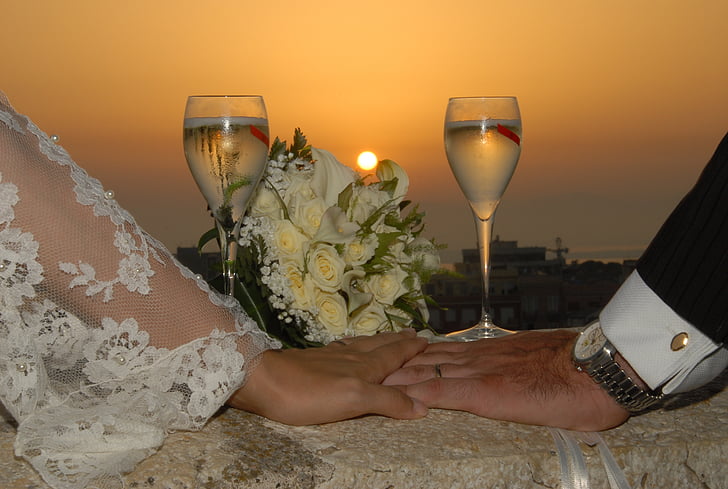 bride and groom hands on white table cloth under sunset