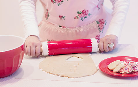 woman holding pink and white rolling pin while baking
