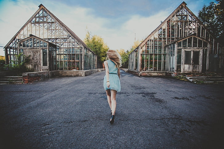woman wearing blue dress walking through building