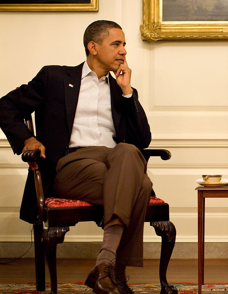 Barack Obama sitting on brown wooden armchair