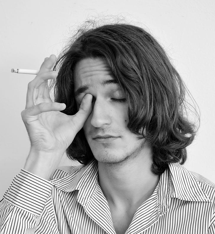 grayscale portrait photo of man holding a cigarette