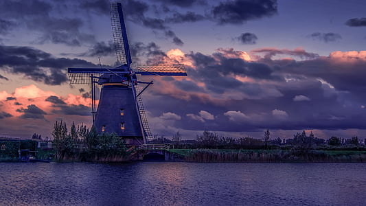 windmill near body of water under cloudy sky