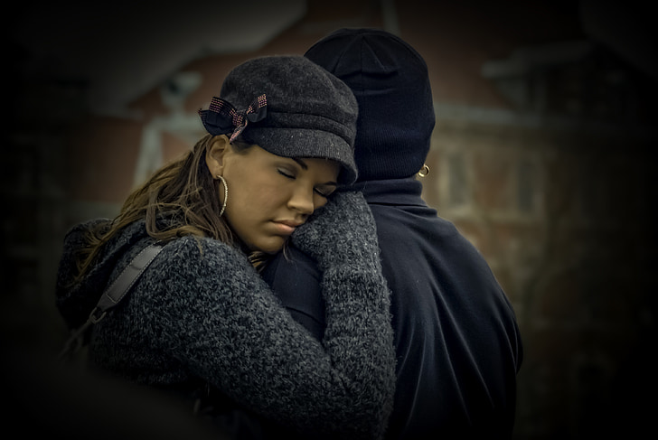 woman hugging person in black hat