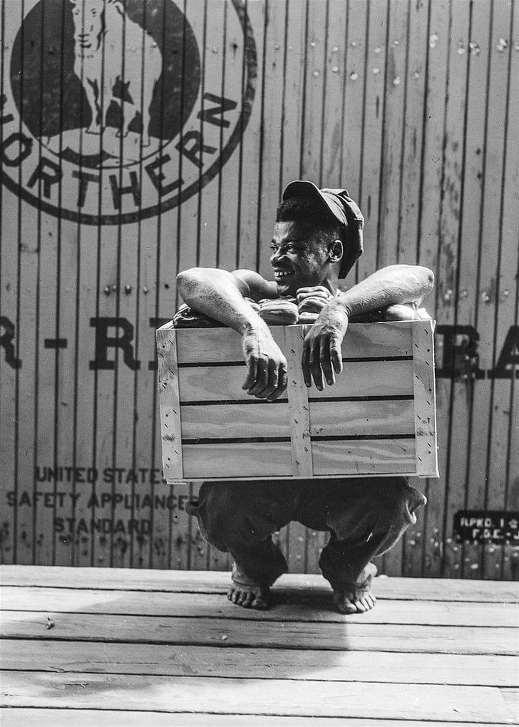 man crouching while holding wooden crate