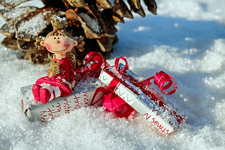 closeup photo of gift box and girl ornament on snow covered ground